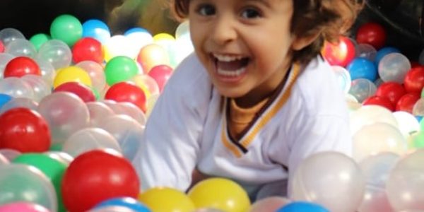 Criança brincando sorridente em uma piscina de bolinhas