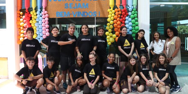 Turma de alunos reunidos com a professora na entrada do colégio prígule